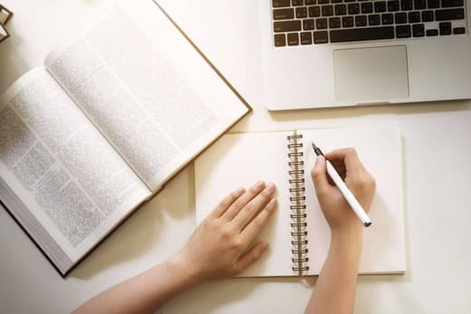 A person writing some notes about the opened book